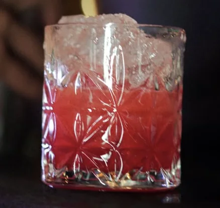 Drink vermelho de morango em copo de cristal lapidado com gelo.