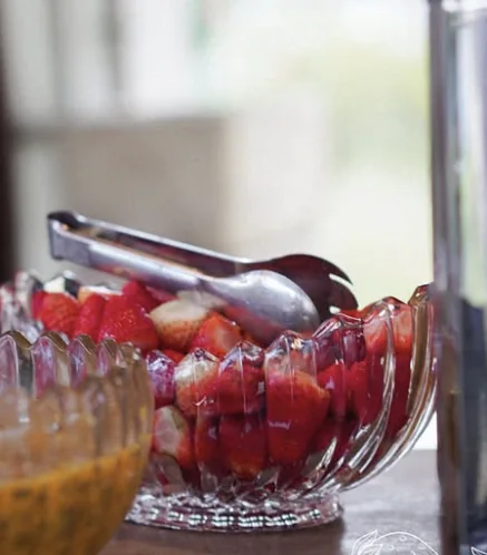 Morangos cortados em bowl de vidro lapidado com pegador de inox.